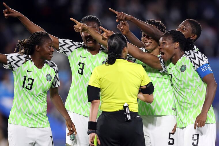 Nigerian players point toward the electronic screen as they protest a yellow card and a penalty awarded against their goalkeeper, Chiamaka Nnadozie.