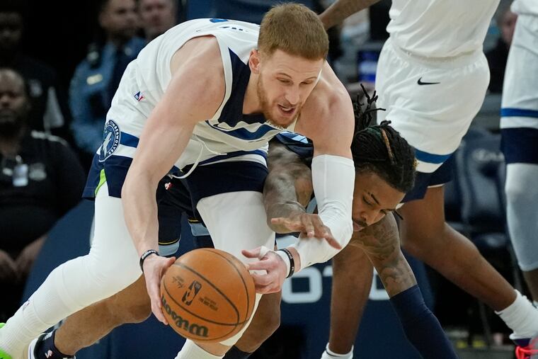 Minnesota Timberwolves guard Donte DiVincenzo (top) wins a battle for the ball with the Grizzlies' Ja Morant on Jan. 11.