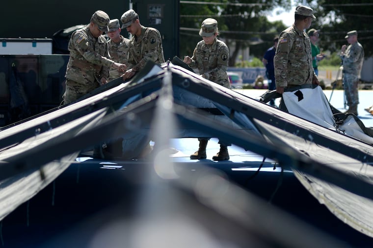 Members of the US army reserve set up tents for portable showers at a tent city set up to house hundreds of people displaced by earthquakes in Guanica, Puerto Rico, Tuesday, Jan. 14, 2020.