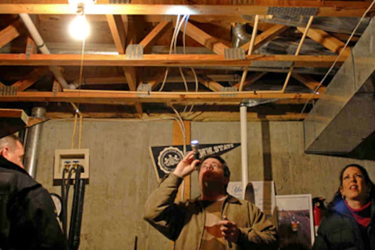 Engineer Harris Gross , of Engineers for Home Inspection, shining his flashlight into the floor joists in the basement of a house Scott and Jodi Whaley hoped to buy. (Tom Gralish / Staff Photographer)