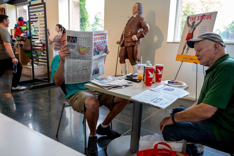 October 9, 2023: Tim M. and Jack F. read their newspapers near the Phillie Phanatic (rear) and Ben Franklin “selfie spot” statues in the Independence Visitor Center.