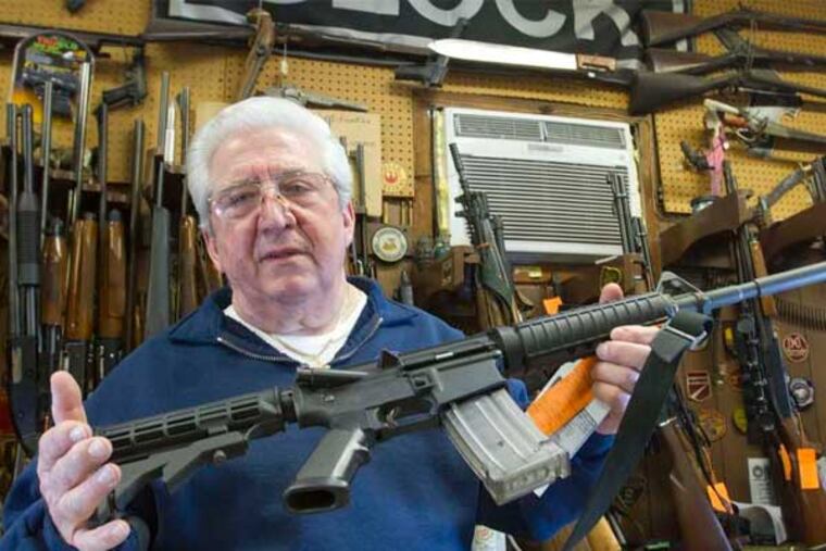 At Delia's Gun Shop on Torresdale Avenue, Fred Delia shows a Bushmaster AR-15 - the sort of weapon under scrutiny in Delaware and elsewhere. (David M Warren / Staff)