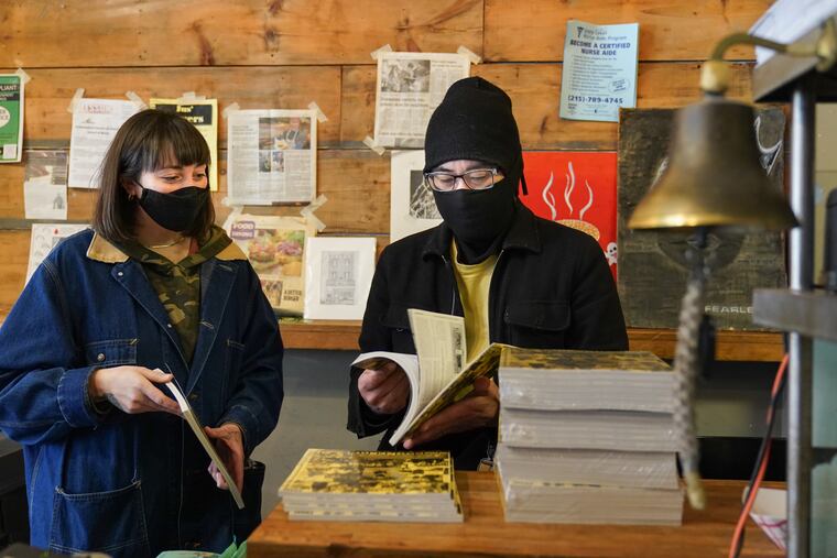 Andrienne Palchick (left) drops off copies of a modern-day "phonebook" to spotlight local businesses and their stories to Josh Kim, at his restaurant Spot Burger, in Brewerytown.