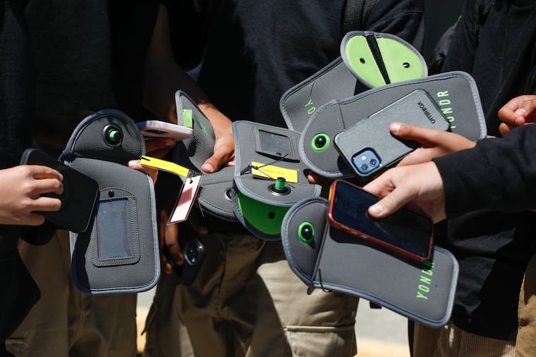 A student uses their cell phone after unlocking the pouch that secures it from use during the school day at Bayside Academy in 2024 in San Mateo, Calif.