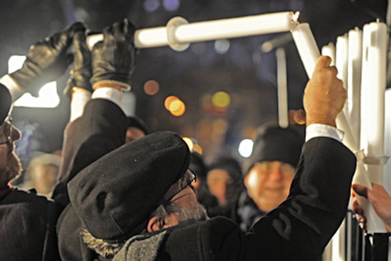 Poland's chief rabbi Michael Schudrich lights the first candle celebrating the beginning of Hanukkah, the Jewish festival of lights, on Grzybowski Square in Warsaw, Poland, on Saturday. ALIK KEPLICZ / Associated Press