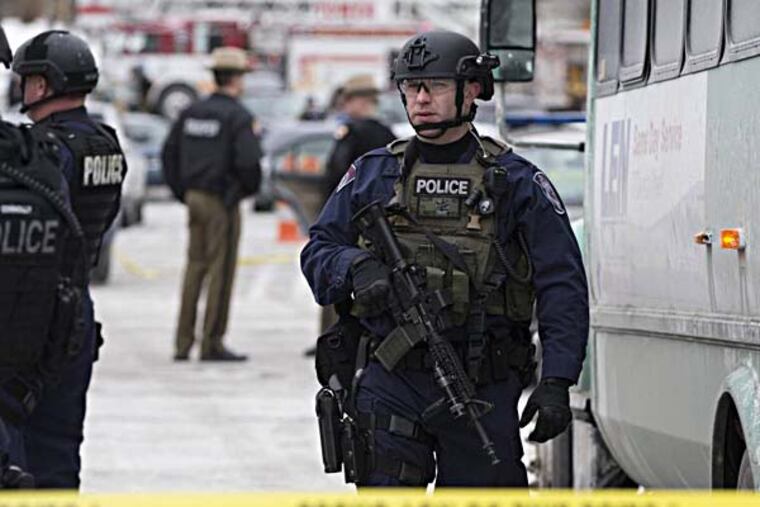 A heavily armed police officer walks on scene after a shooting at The Mall in Columbia on Saturday, Jan. 25, 2014 in Columbia, Md. Police say three people died in a shooting at the mall in suburban Baltimore, including the presumed gunman. (AP Photo/ Evan Vucci)