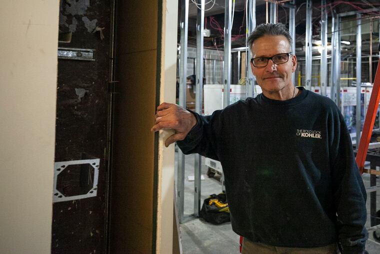 Lou DiOrio poses for a portrait by the hole in the wall at a construction site in the Curtis building at 6th and Walnut, where he found a woman's bag containing her belongings from 20 years ago.