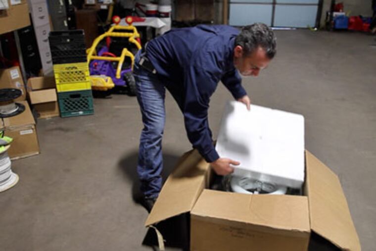 Mike Antonelli, president at National Energy Solutions Inc in Levittown, Pa, unpacks an energy efficient light. ( LAURENCE KESTERSON / Staff Photographer )