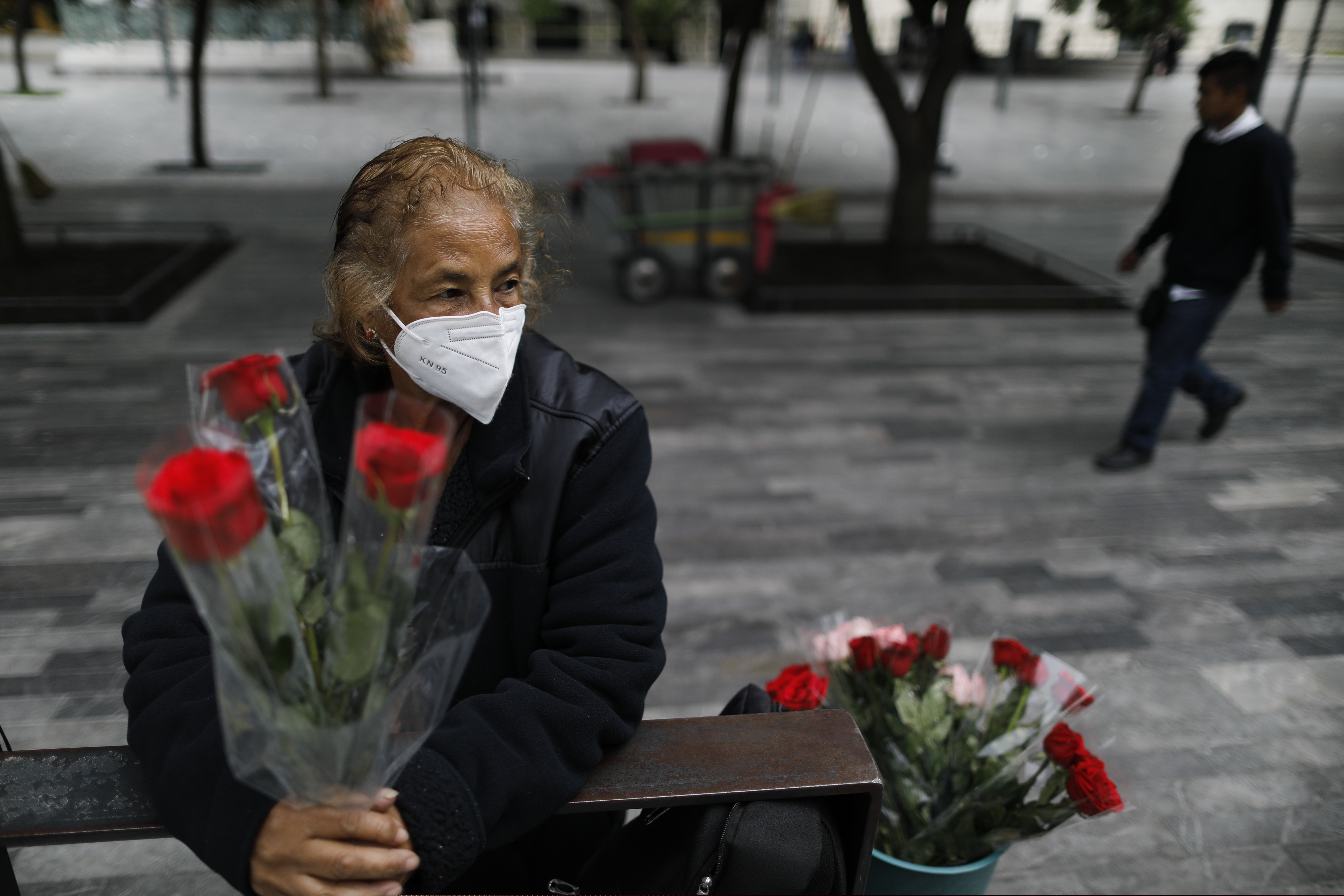 Wearing a mask to curb the spread of the new coronavirus, Martha Gonzalez Reyes, 76, sells roses outside Metro Hidalgo in central Mexico City.