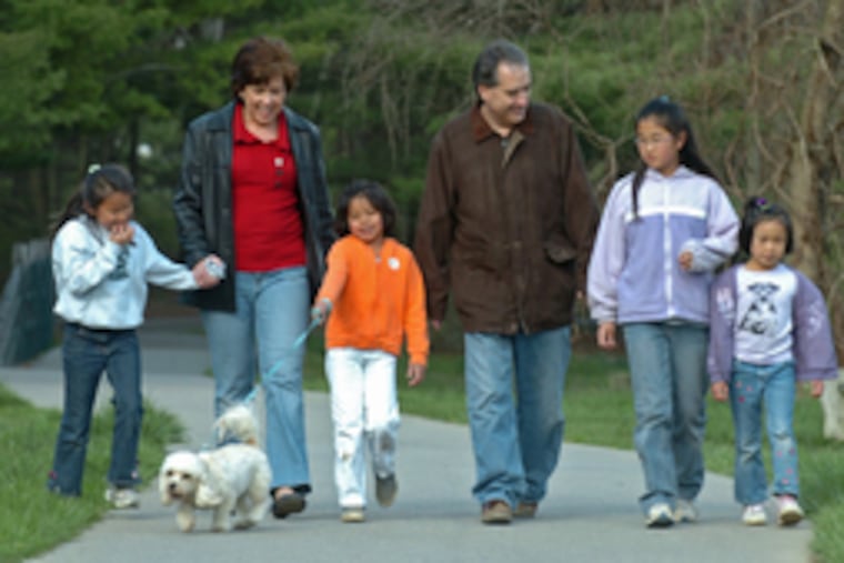 Denise Glennon and her husband, Gary Haubold, with daughters (from left) Clara, 9; Sophina, 6, walking dog Violet; Lucy, 10; and Cecilia, 7. Sophina is Cambodian; her sisters are Chinese.