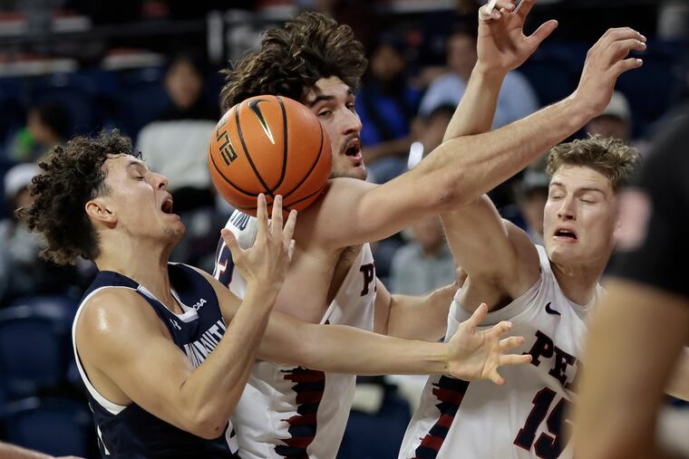 Penn’s Nick Spinoso, center and Andrew Laczkowski, right get tangles with Monmouth's Xander Rice, left in the final game of the three-day Cathedral Classic at the Palestra.