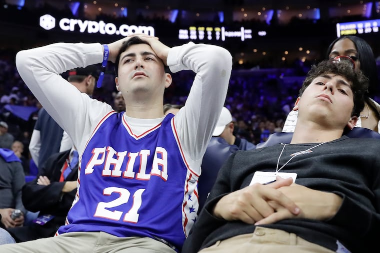 Two dejected Sixers fans try to watch the end of the team's 99-90 loss Thursday night to the Miami Heat in Game 6 of the Eastern Conference semifinals.