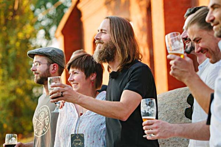 In this Saturday, July 19, 2014, photo provided by Stone Brewing Co., Stone Brewing Co. CEO and Co-founder Greg Koch, center, toasts the crowd after announcing the Escondido, Calif., brewery's plan to build a brewery and bistro in Berlin. Stone Brewing Co. is spending about $25 million to renovate a historic gas works building into a brewery, packaging and distribution center, restaurant and garden set to open late next year. Stone Brewing Co., one of the top 10 biggest craft breweries in the U.S., will make beer for its bistro and distribution throughout Germany and Europe. (AP Photo/Stone Brewing Co., Frederik Ferschke)