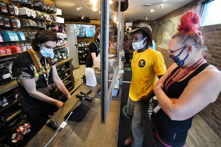 Budtender Kelley Dearing helps customers Timothy Benison and Sharon Stricklan with their purchases at the Greenhouse, a recreational and medical marijuana dispensary, in Walled Lake, Mich., on June 7, 2021. An estimated 321,000 Americans now work in the marijuana industry, a 32% increase from last year.