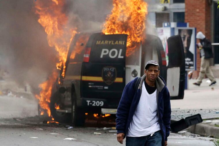 A man walks past a burning police van during unrest after the funeral of Freddie Gray in Baltimore. Gray died from spinal injuries about a week after he was arrested and transported in a Baltimore Police Department van.