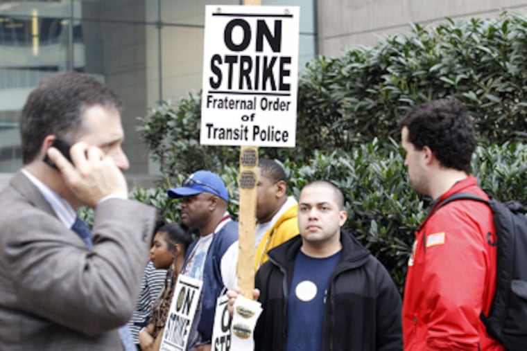 Transit Police Officer Jorge Alicea, a three-year veteran, holds a picket sign near the SEPTA concourse in Center City. (Yong Kim / Staff Photographer)