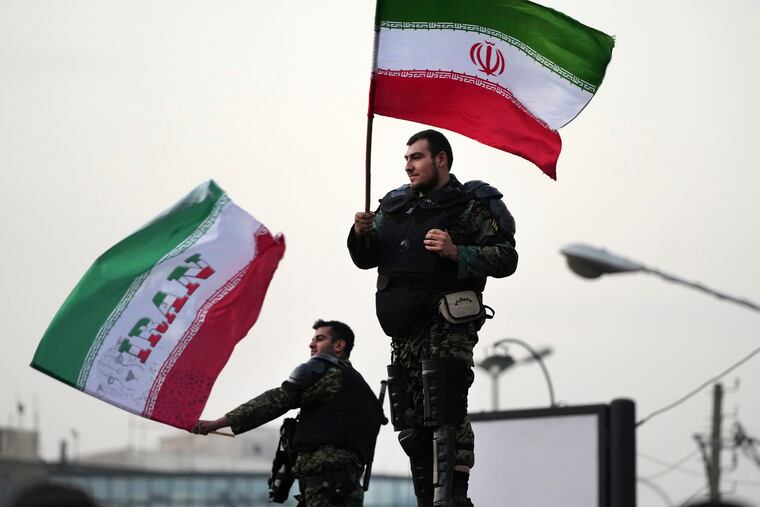 Two anti-riot police officers wave Iranian flags during a street celebration after Iran defeated Wales at the World Cup.