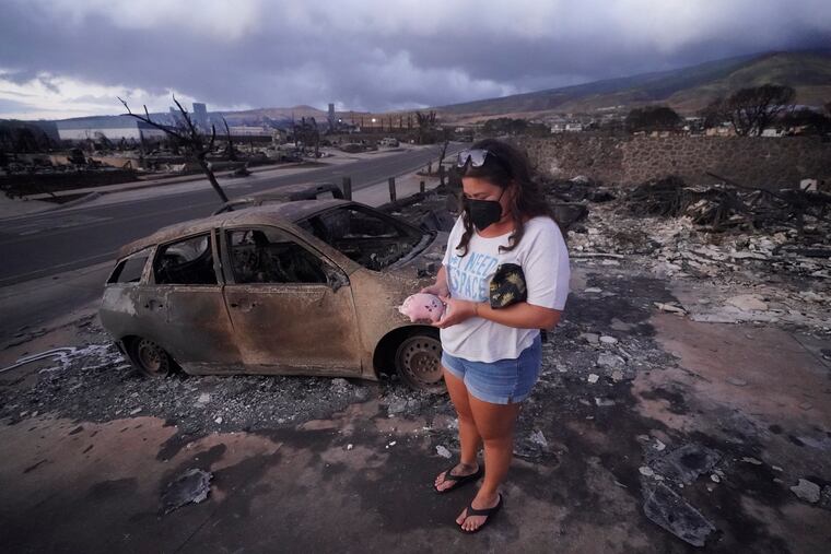 Summer Gerlingpicks up her piggy bank found in the rubble of her home following the wildfire last week in Lahaina, Hawaii.
