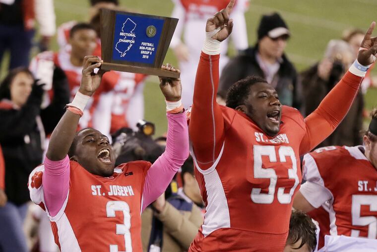 St. Joseph's Jada Byers (No. 3) and Sean Morris (No. 53) hold up trophy after 41-22 victory over Holy Spirit in Non-Public 2 state final.