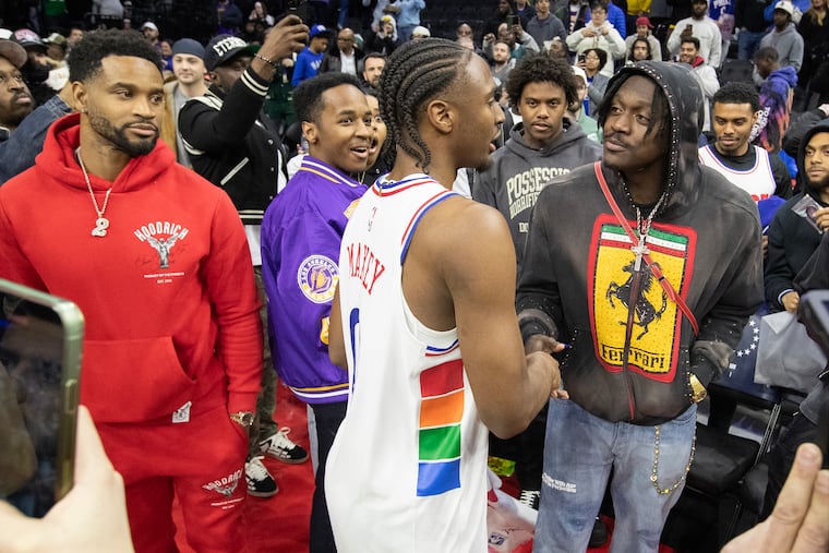 Tyrese Maxey of the Sixers greets the Eagles' Darius Slay (left) and A.J. Brown after the victory over the Lakers on Tuesday.