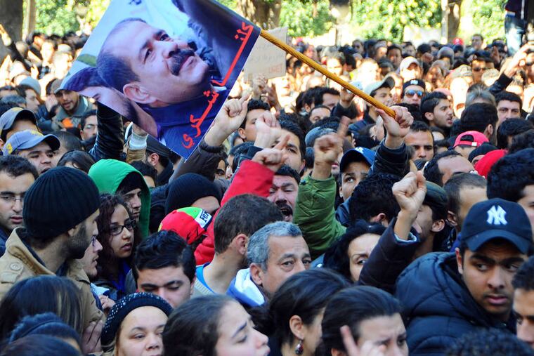 Protesters gather on Tunis' main avenue after opposition leader Chokri Belaid, seen on the flag, was slain as he left for work Wednesday. Tunisia, the first "Arab Spring" nation, is seeing rising turmoil.
