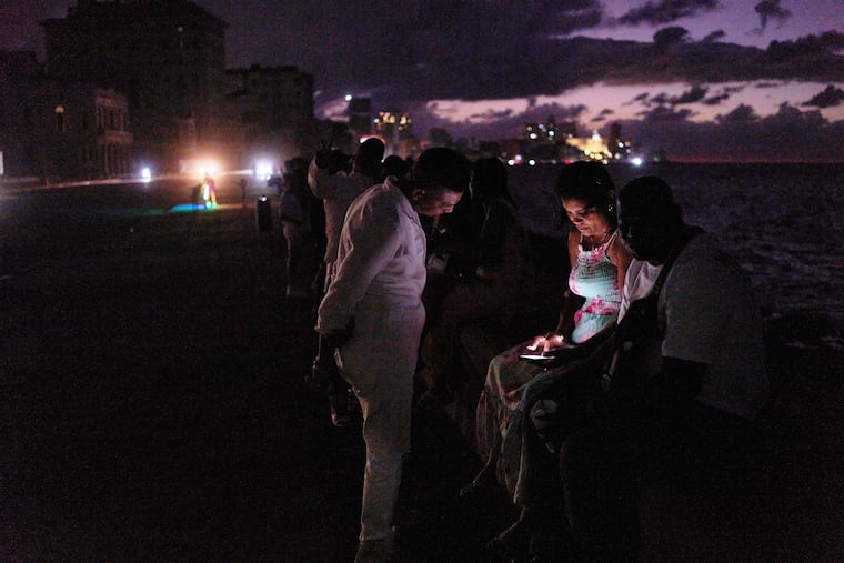 People spend the night in the dark on the Malecon during a blackout in Havana, Cuba, Saturday, March 21, 2026.