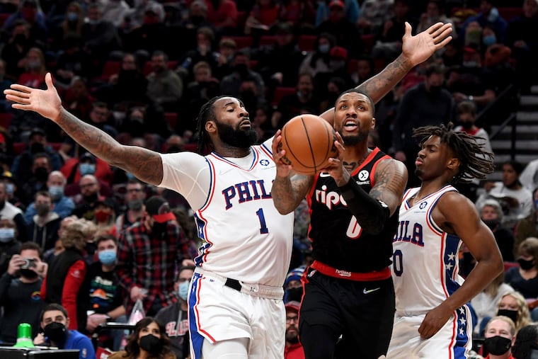 Portland Trail Blazers guard Damian Lillard, center, drives to the basket on Philadelphia 76ers center Andre Drummond, left, and guard Tyrese Maxey, right, during the second half of an NBA basketball game in Portland, Ore., Saturday.