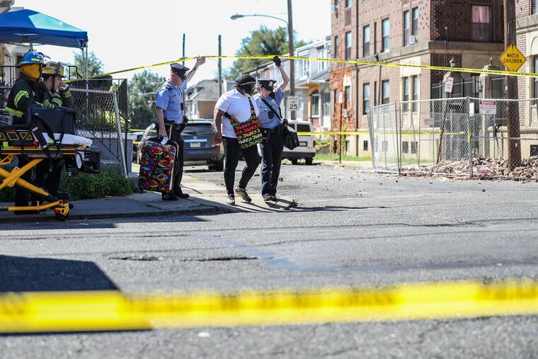 Philadelphia police help a resident with their bag outside of a building at 1228 Lindley Ave. in North Philadelphia on Sept. 14. The building was in danger of collapse, resulting in residents evacuating. To the right is an area of the building that came off.