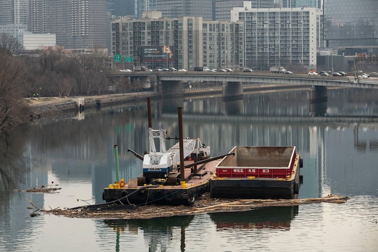 Debris collects on barges in the Schuylkill River in Philadelphia, Pa. on Thursday, January 14, 2021. A contractor dredging the Schuylkill River along Philadelphia’s iconic Boathouse Row has stopped work, claiming it needs more money to continue working after it found too much large debris such as telephone poles.