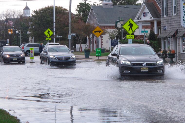 Cars kick up spray while driving through a flooded street in Bay Head, N.J., during a “sunny day” flood in 2019 caused by tides and rising sea levels.