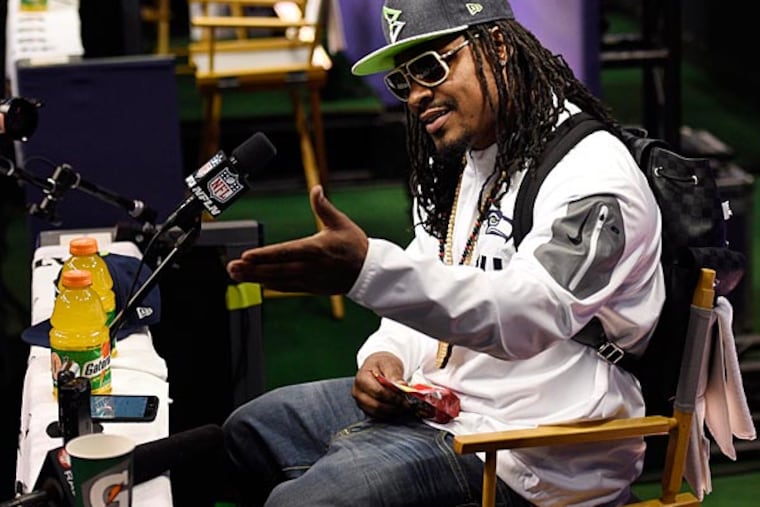 Seattle Seahawks running back Marshawn Lynch sits at his podium during media day for Super Bowl XLIX at US Airways Center. (Kyle Terada/USA Today)