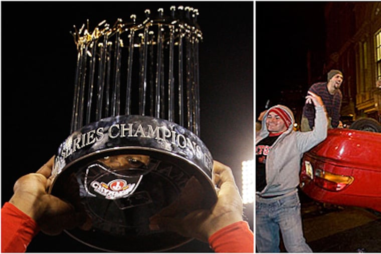 Ryan Howard, left, holds up World Series Champions trophy last night, as fans, right, took to the streets and celebrated to an overturned car on Walnut Street near Broad Street. (AP / Jessica Griffin / Staff Photographer)