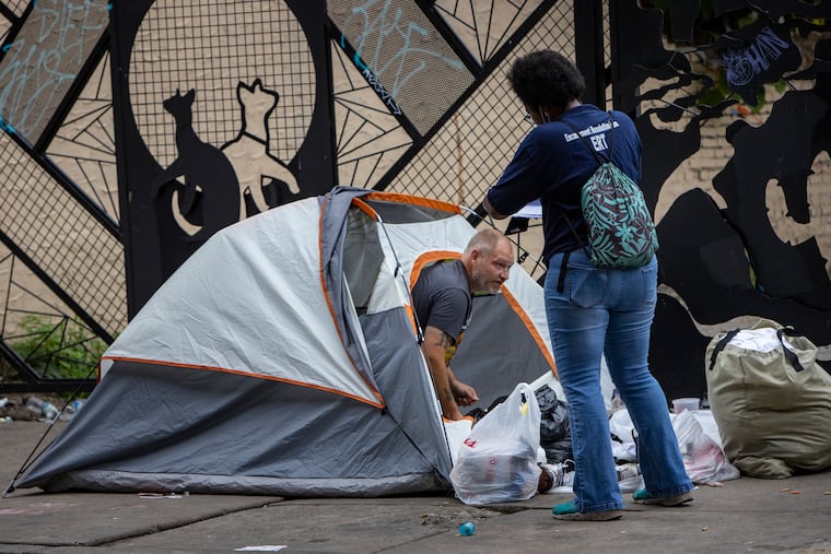A member of the Encampment Resolution Team speaks with a homeless camper outside his tent on the sidewalk along Kensington Avenue at E. Willard Street. The City of Philadelphia, police and social services were on Kensington Avenue on Wednesday morning August 18, clearing the avenue of homeless camper. The homeless residents along Kensington were offered assistance by the city with relocating.