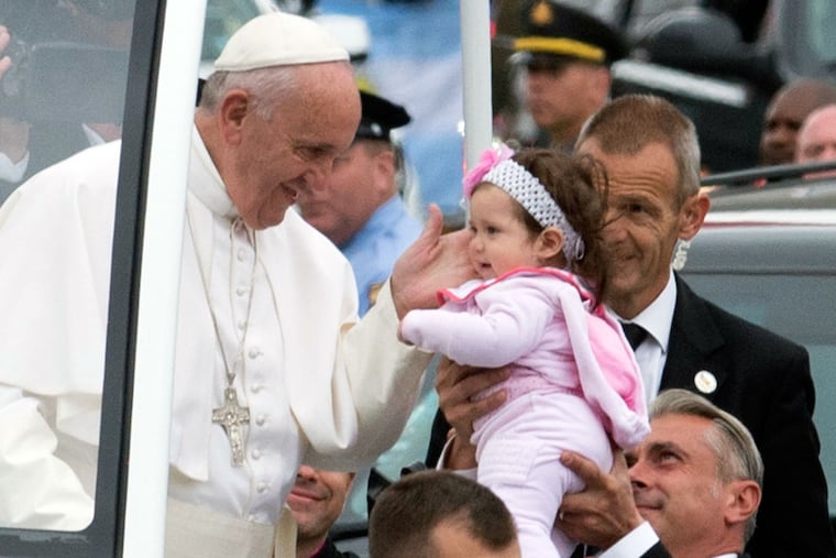 Pope Francis touches a toddler after kissing her at a stop in Logan Square on the Benjamin Franklin Parkway in Philadelphia on Sunday, Sept. 27, 2015.