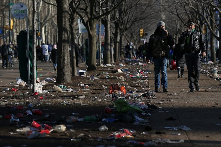 People walk past trash along the Ben Franklin Parkway after the Eagles’ Super Bowl parade on Thursday, Feb. 8, 2018.