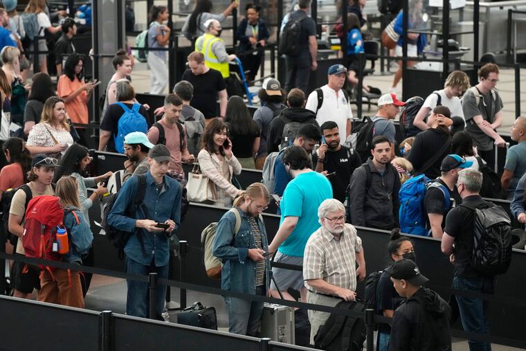 Travelers wait in long lines at a security checkpoint in Denver International Airport early July in Denver.