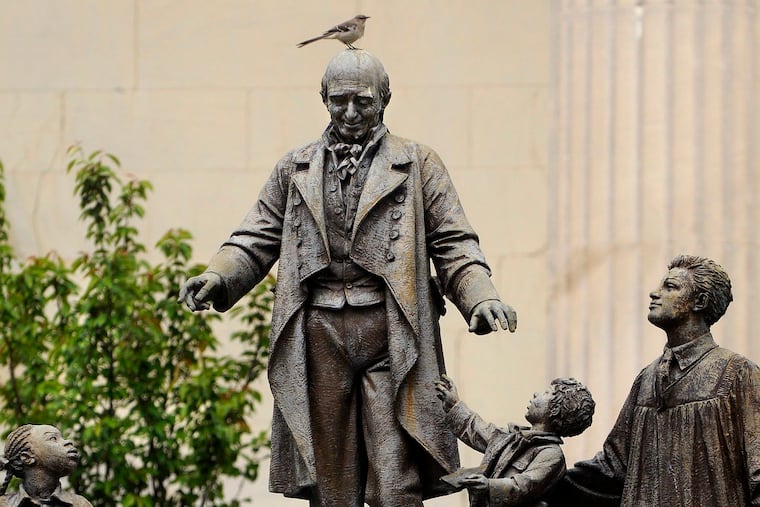 A bird lands atop "The Spirit of Girard," a sculpture by Bruno Lucchesi, in front of Founders Hall at Girard College.