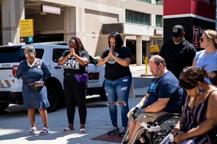 Members of the community affected by gun violence along with antiviolence advocates bow their heads as the Rev. G Lamar Stewart Sr., senior pastor at Taylor Memorial Baptist Church, prays before they head out for the “Restore Our City” march outside of Temple University Hospital in Philadelphia on Saturday.