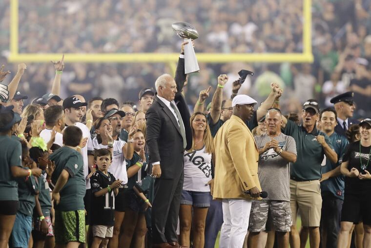 Eagles owner Jeffrey Lurie holds up the Super Bowl trophy next to former Eagle Brian Dawkins before the Super Bowl banner was unveiled.