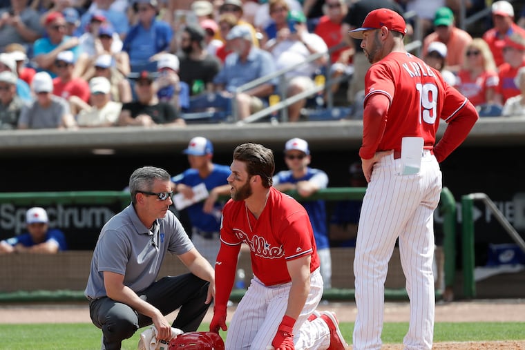 Phillies Bryce Harper yells towards Blue Jays pitcher Trent Thornton with Manager Gabe Kapler and assister trainer.Chris Mudd during the sixth-inning in a spring training game on Friday, March 15, 2019 at Spectrum Field in Clearwater, FL.