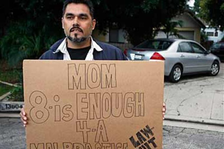 Whittier resident Ulyses Guzman holds a sign outside the home of the Suleman family in Whittier, Calif. on Friday, Feb. 6, 2009. (AP Photo/Damian Dovarganes