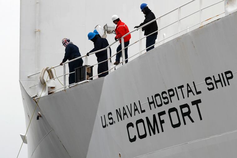Workers prepare to toss lines ashore during the arrival of the USNS Comfort in New York on Monday.