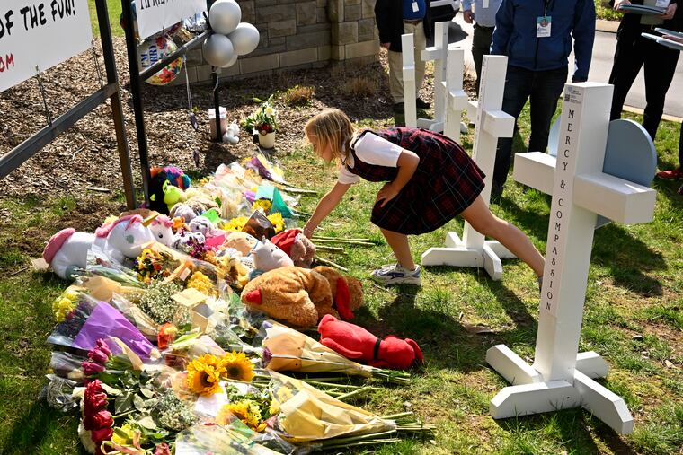 A young girl places an item at a growing memorial at an entry to Covenant School in Nashville, Tenn. The attack at the Christian elementary school killed six people, including three children.