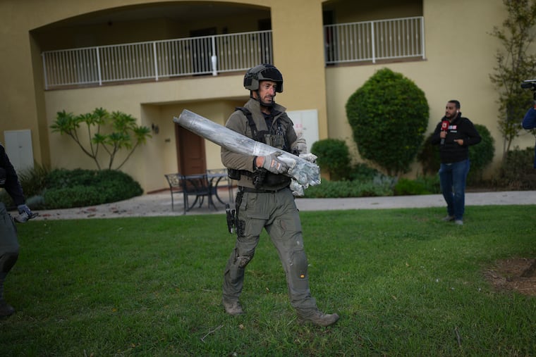 An Israeli bomb squad officer carries the remains of a rocket that was fired from Lebanon in Kibbutz Kfar Blum, northern Israel, on Sunday.