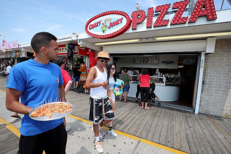 Abdul Abham holds free samples of pizza outside of Crazy Junky Pizza on the boardwalk in Wildwood, N.J. on Sunday, July 17, 2022.