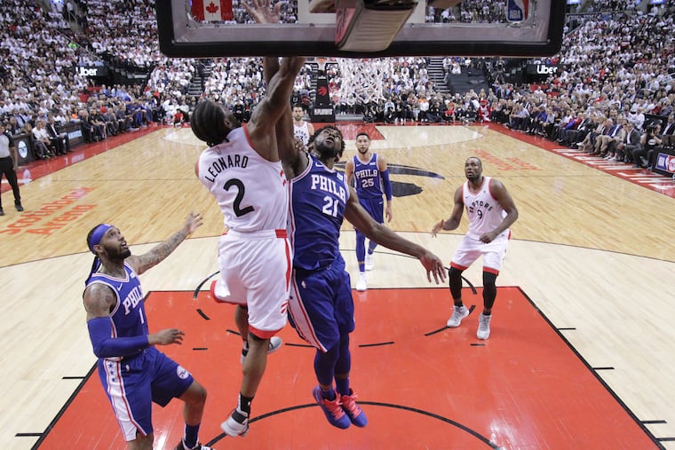 Kawhi Leonard, #2, 2nd from left, of the Raptors dunks over Joel Embiid, center, of the Sixers during the 2nd half of their NBA Eastern Conference semifinal game at the Scotiabank Arena in Toronto on May 7, 2019.