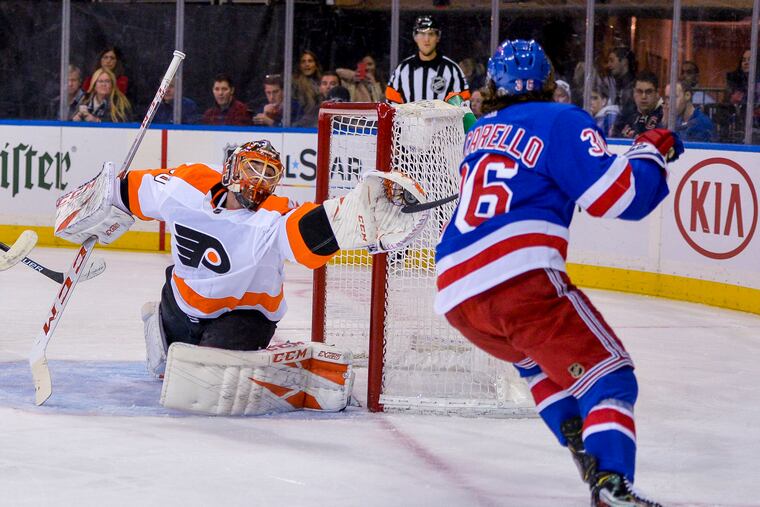 Michal Neuvirth gets his glove on puck and stick of Rangers right wing Mats Zuccarello during the second period of the Flyers' win on Sunday.