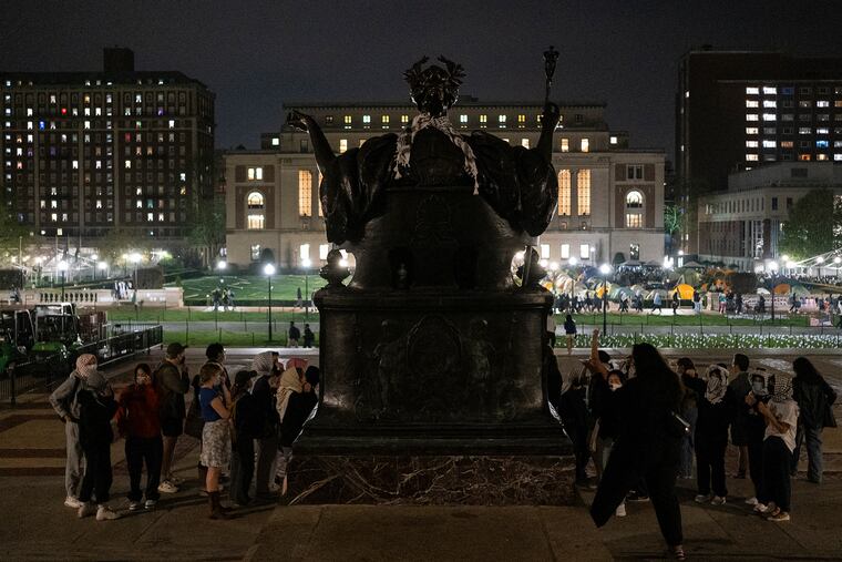 Student protesters with the Gaza Solidarity Encampment place a keffiyeh on Columbia University's Alma Mater on Tuesday in New York.
