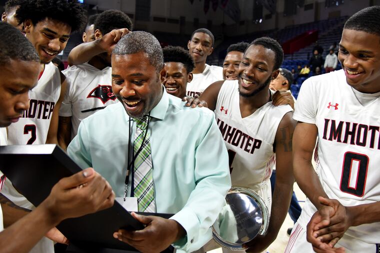 Imhotep coach Andre Noble looks over the Public League boys' basketball championship trophy after his Panthers defeated Martin Luther King, 66-37, at the Palestra on Feb. 25, 2018.