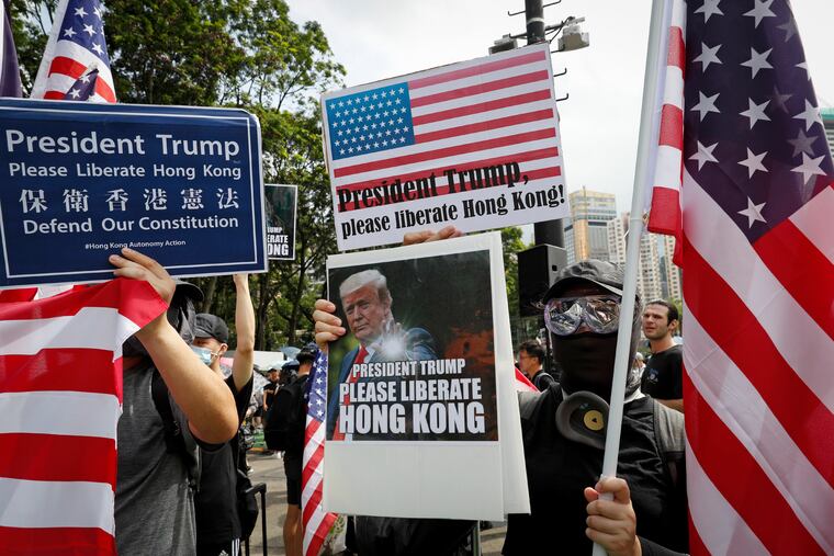 Protesters hold a placard featuring U.S. President Donald Trump and U.S. flags as they take part in a march at Victoria Park in Hong Kong, Sunday, July 21, 2019. Thousands of Hong Kong protesters marched from a public park to call for an independent investigation into police tactics.(AP Photo/Vincent Yu)